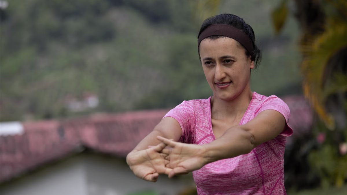 A woman in sportswear stretching outdoors with a natural background.
